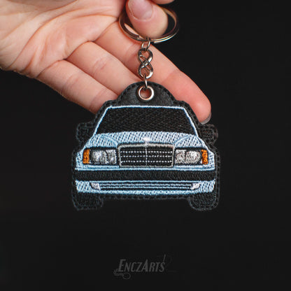 Haftowany brelok EnczArts przedstawiający zielony Mercedes W124 rękodzieło inspirowane klasykami motoryzacji.