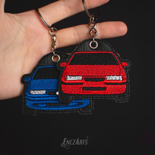 Haftowany brelok EnczArts przedstawiający Opla Calibrę rękodzieło inspirowane klasykami motoryzacji.
