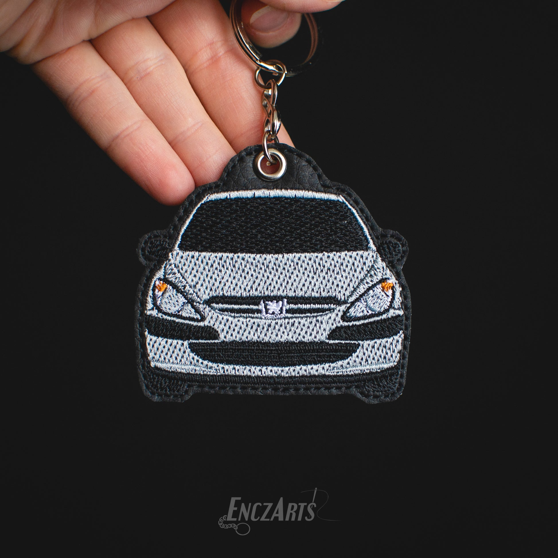 Haftowany brelok samochodowy EnczArts model Peugeot 307 w kolorze srebrnym.