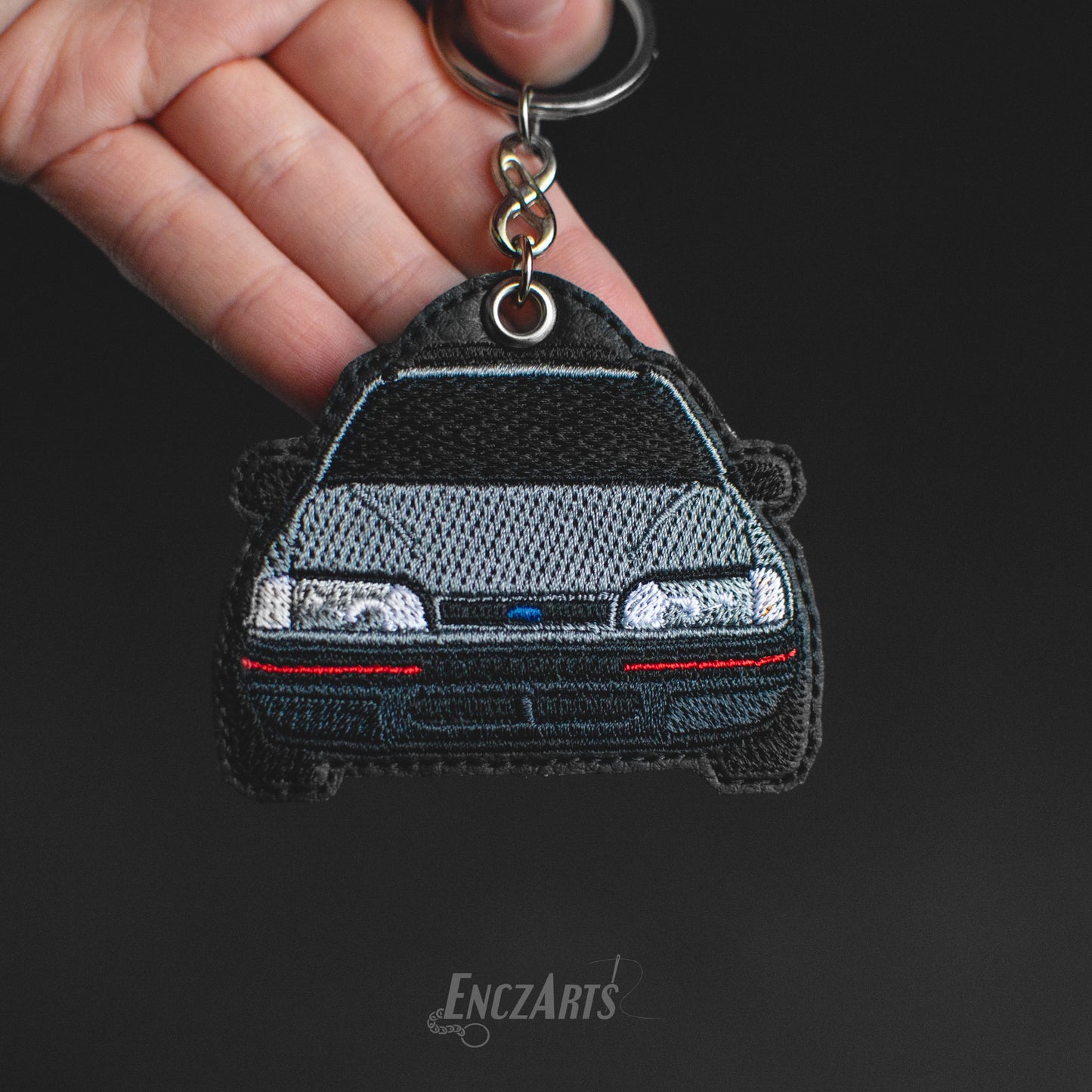 Haftowany brelok samochodowy EnczArts model Ford Sierra w kolorze srebrnym.